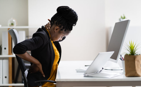 Lady working at desk holding her neck and back in pain 